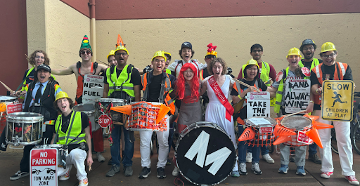 Joined by several members of the Cardinal Women’s Basketball team, the drum section attached Marg signs to harnesses and wore them as armor-like breast plates. Costumes and instruments were embellished with traffic signal  hats, STOP sign epaulets and traffic cones. Shuttle route signs were taped with “Take the Axe!”  and “Beat CAL” slogans. 
