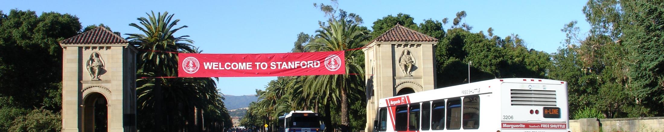 Marguerite bus on Palm Drive below "Welcome to Stanford" banner