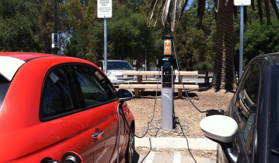Red vehicle at electric vehicle charging station on campus.