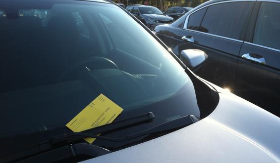 vehicle with a yellow parking citation on the windshield